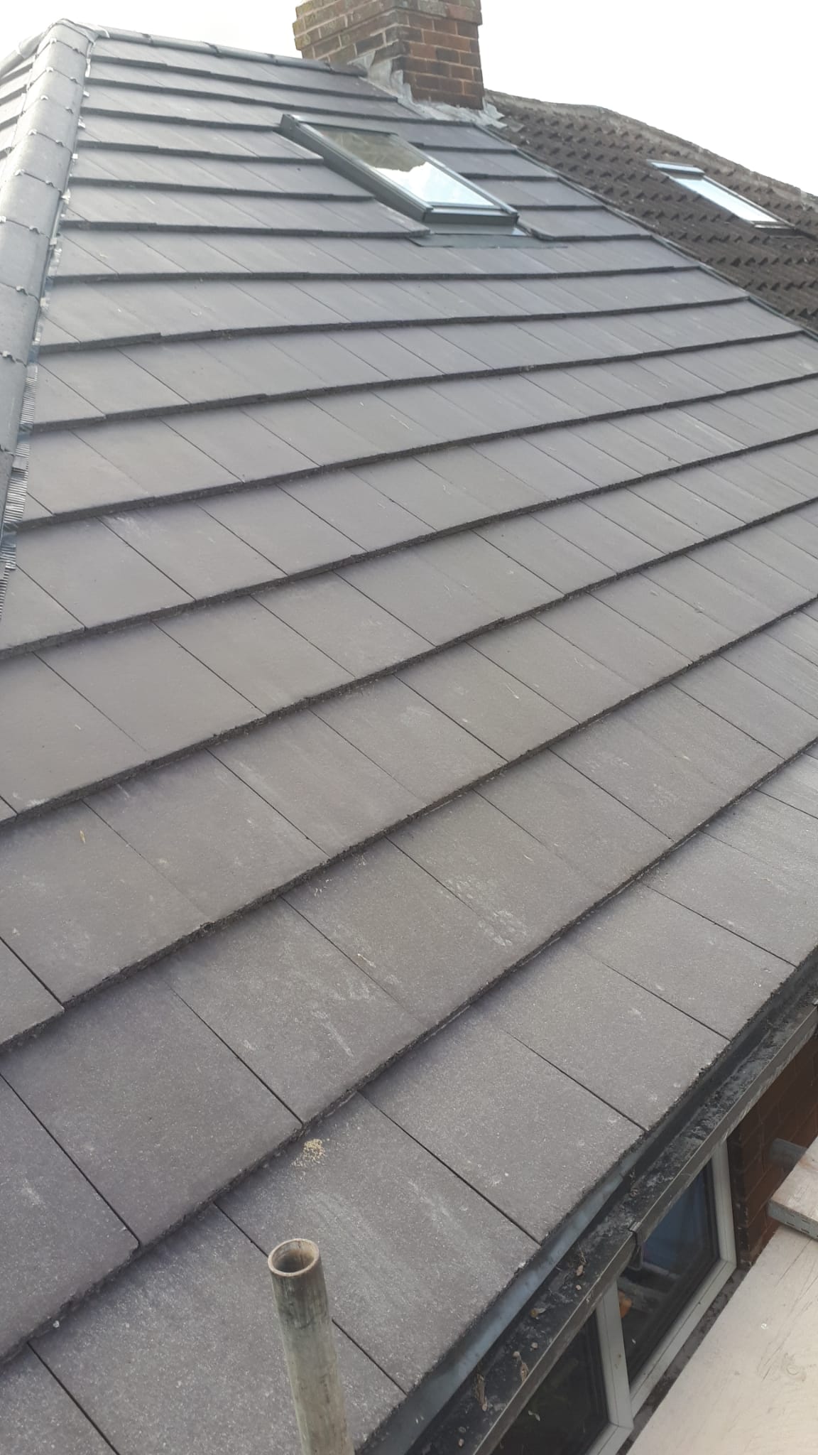 New tiled roof next to old worn roof showing the difference