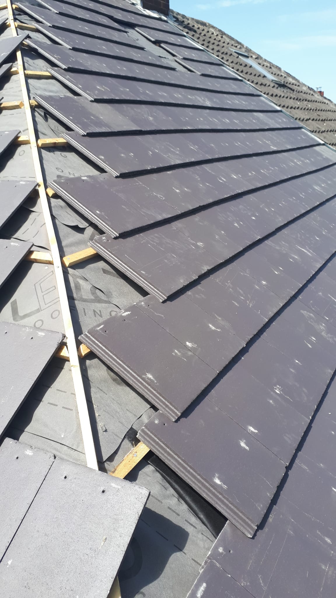 New grey tiles being laid over membrane and battens